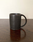 Rila Black Straight Mug, textured porcelain by Kaneko Kohyo, Japan, on wooden surface. 200cc capacity, 8.5cm height, matte finish.