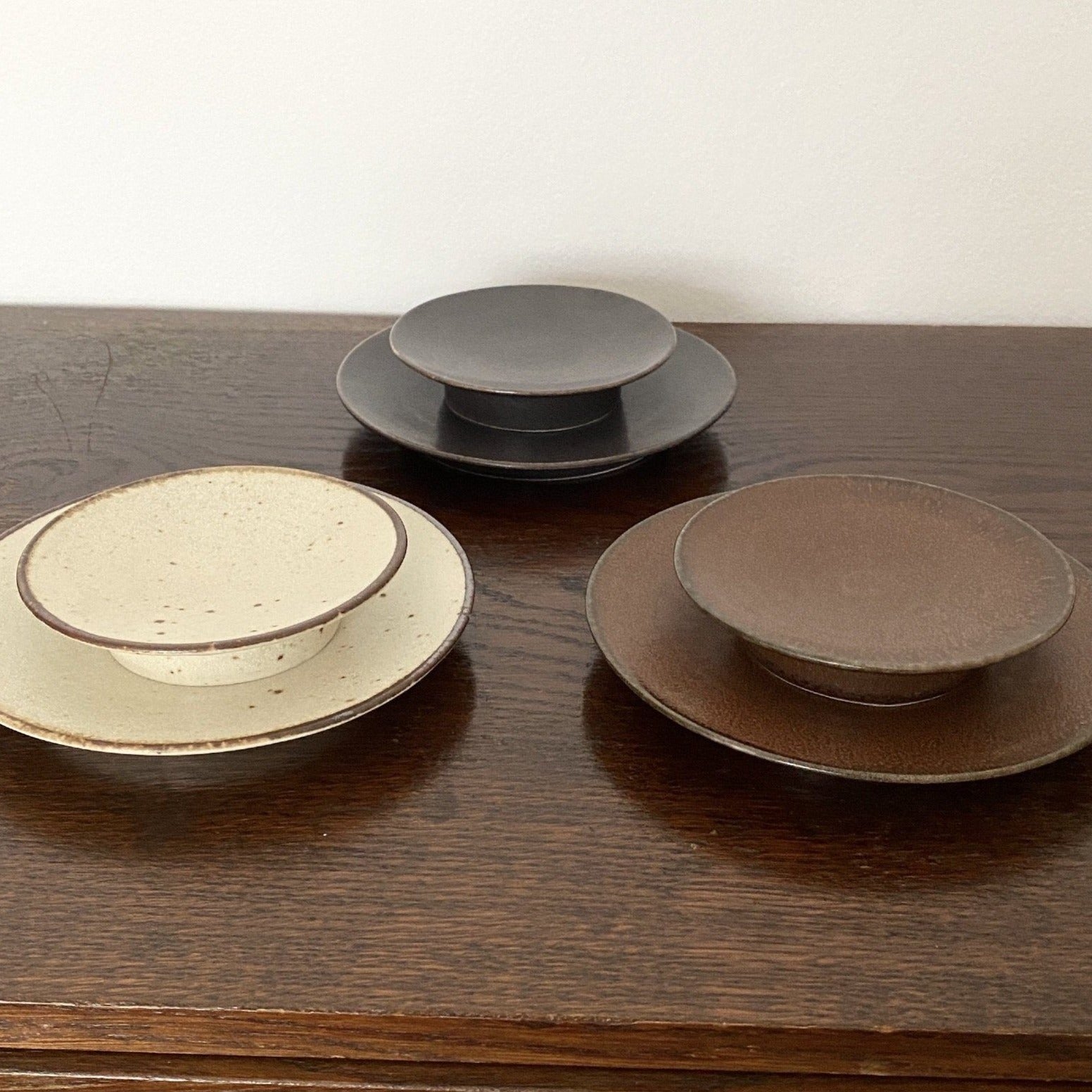 Three elegant textured porcelain dishes, including the Rila Black creation, by Kaneko Kohei, displayed on a wooden surface.