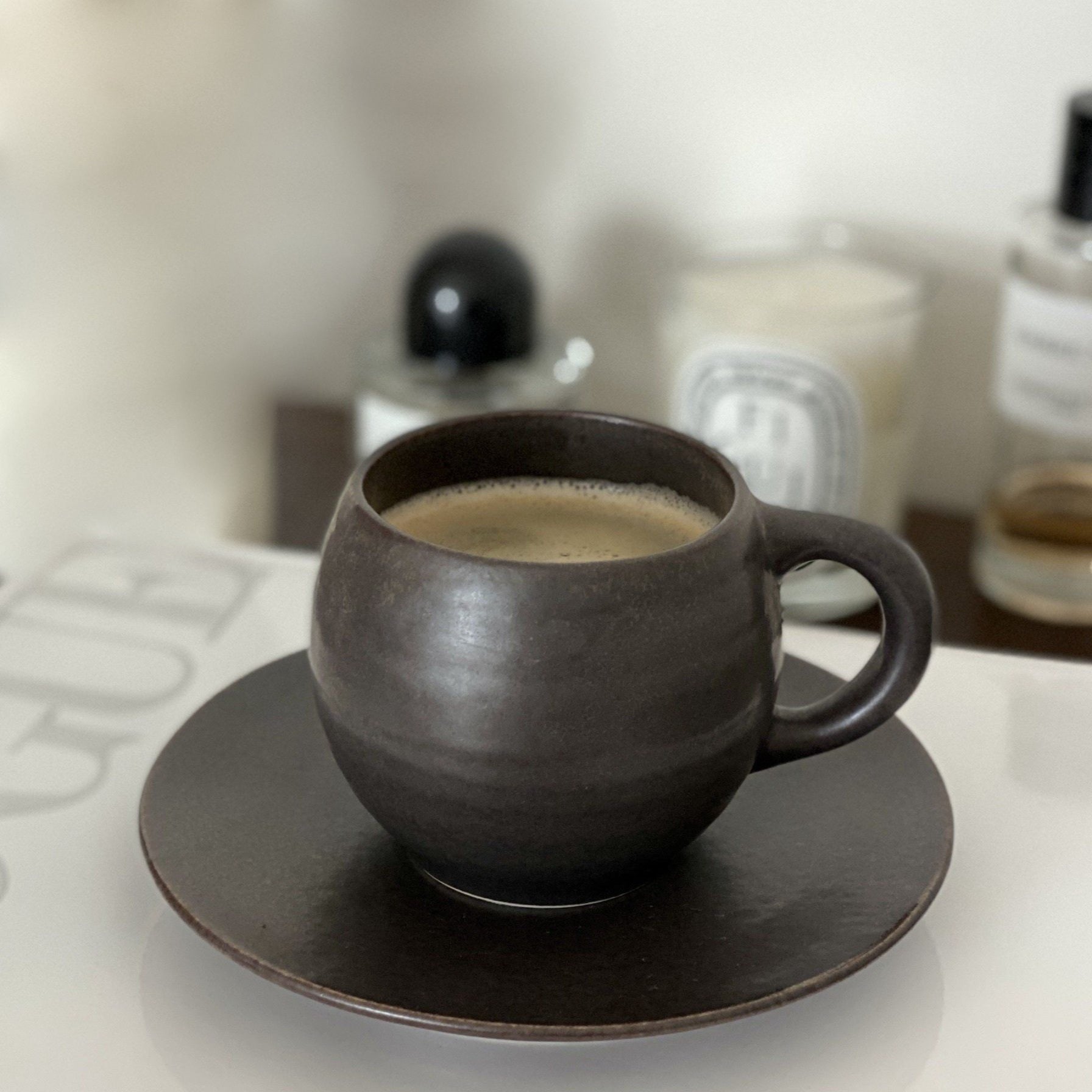 Rila Black Mug from Kaneko Kohyo, textured porcelain, on a table, filled with coffee, microwave-safe, matte finish, 340ml capacity.