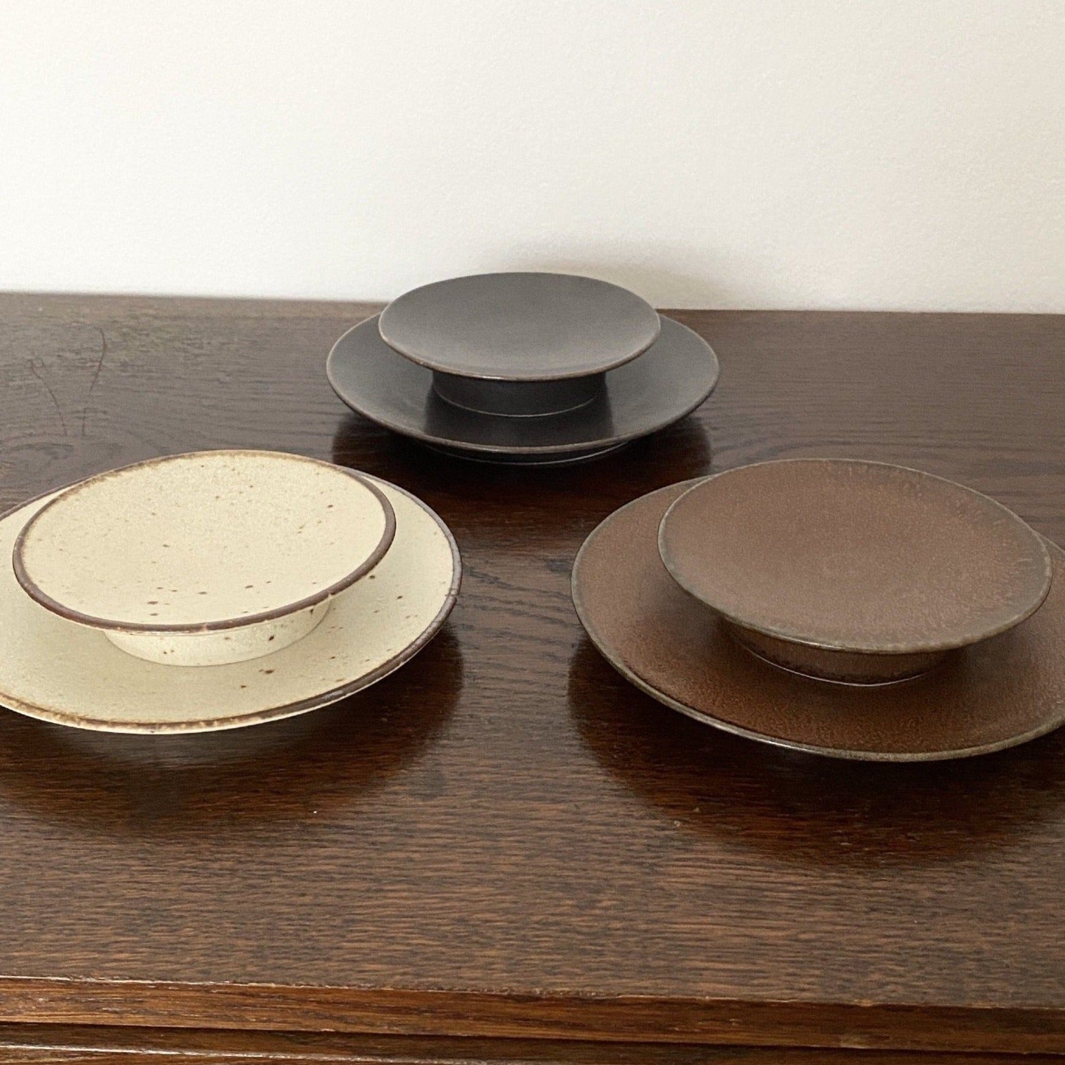 Japanese porcelain plates by Kaneko Kohyo, including Rila Brown, featuring tasteful textures and matte finish, displayed on a wooden table.