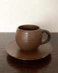 Rila Brown Mug on matching saucer, porcelain with textured matte finish, crafted by Kaneko Kohyo, perfect for microwave use.
