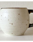 Ivory porcelain mug with a textured matte finish and dark handle, crafted by Kaneko Kohyo, microwave-safe and stackable.