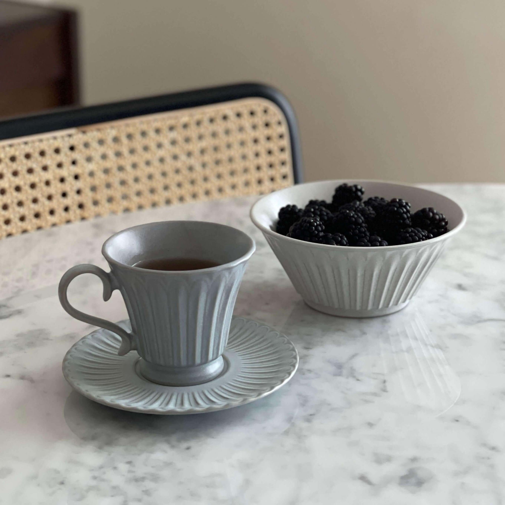 Porcelain cup and Storia Bowl with blackberries on marble table for elegant dining ambiance.