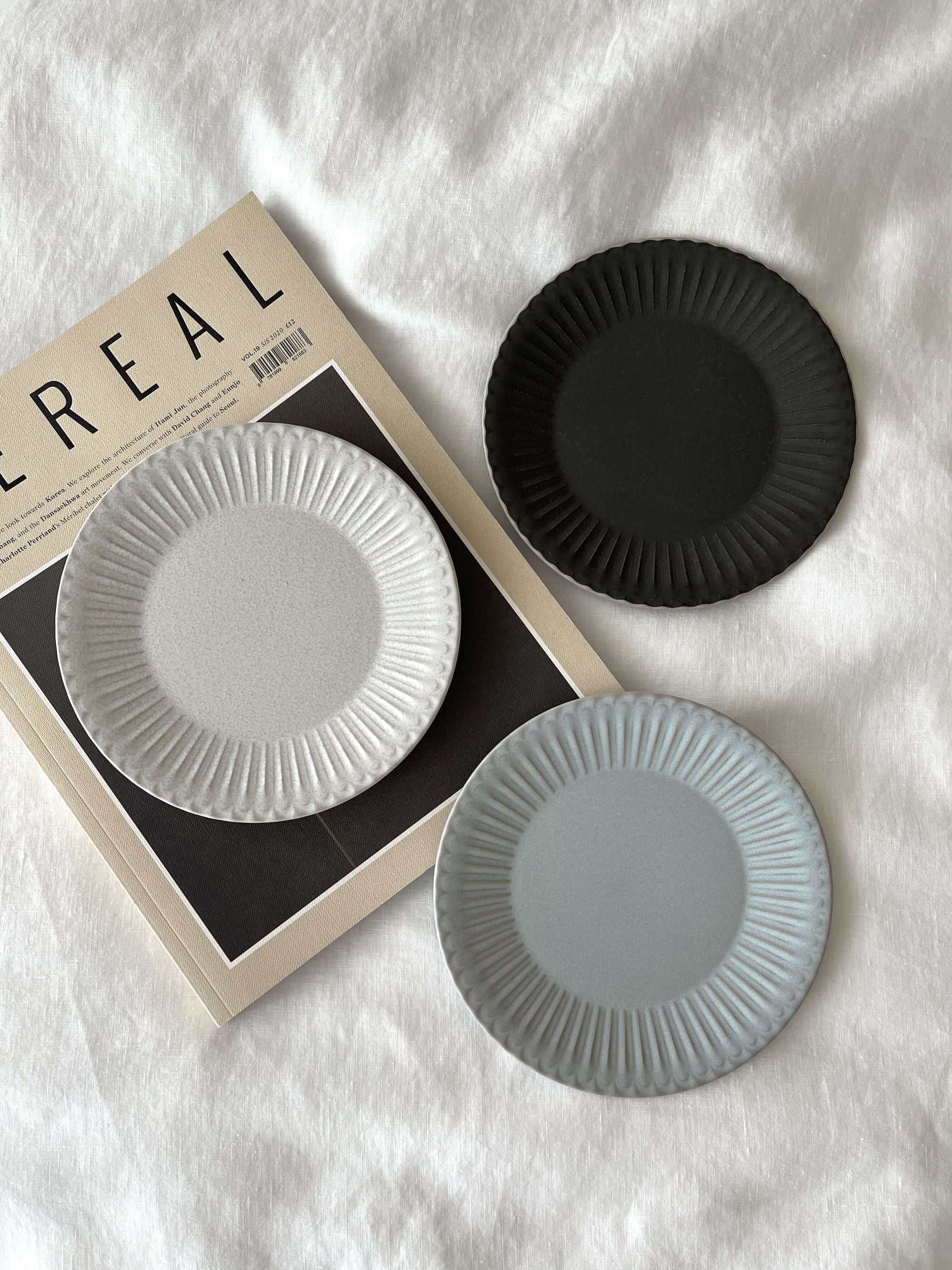 Elegant porcelain plates with lace edges on a magazine, evoking nostalgia and sophistication in dining tableware.