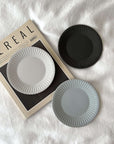 Elegant porcelain plates with lace edges on a magazine, evoking nostalgia and sophistication in dining tableware.