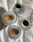 Elegant tea set with lace-edged plates, cups of tea, cookies, and a pastry on a soft cloth, evoking a nostalgic, romantic feel.