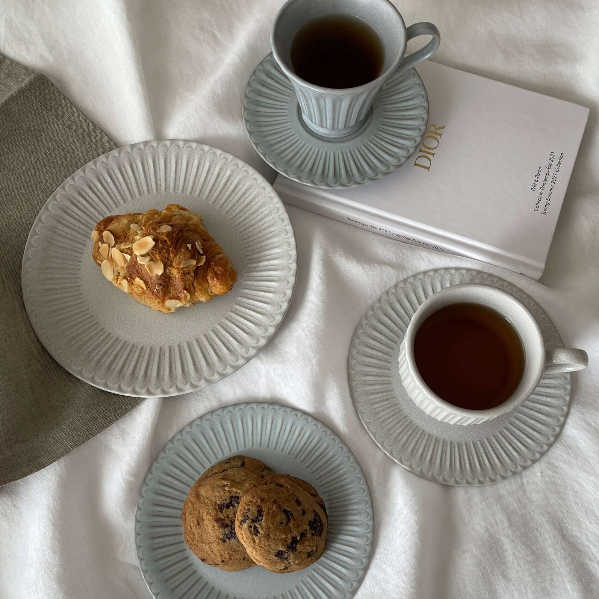 Elegant porcelain plates and cups with cookies and pastry on a table, featuring soft lace edges and a nostalgic design.