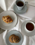 Elegant porcelain plates and cups with cookies and pastry on a table, featuring soft lace edges and a nostalgic design.