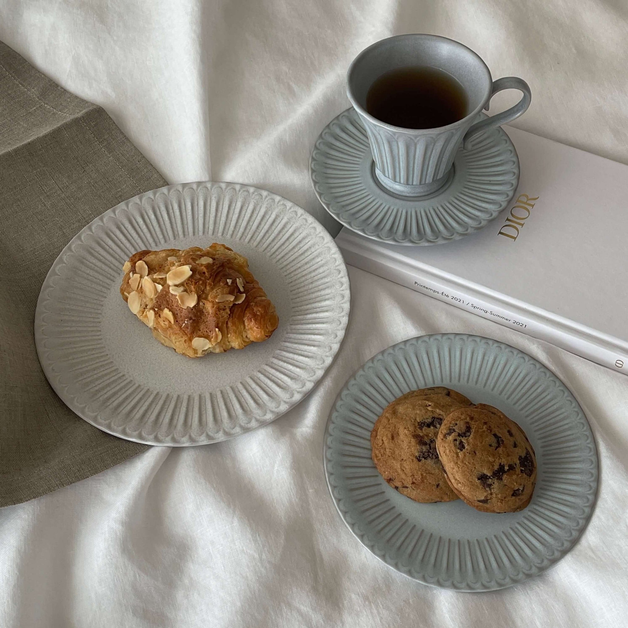 Elegant porcelain plates with pastries and a teacup on a book, showcasing a nostalgic and romantic dining experience.