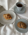 Elegant porcelain plates with pastries and a teacup on a book, showcasing a nostalgic and romantic dining experience.