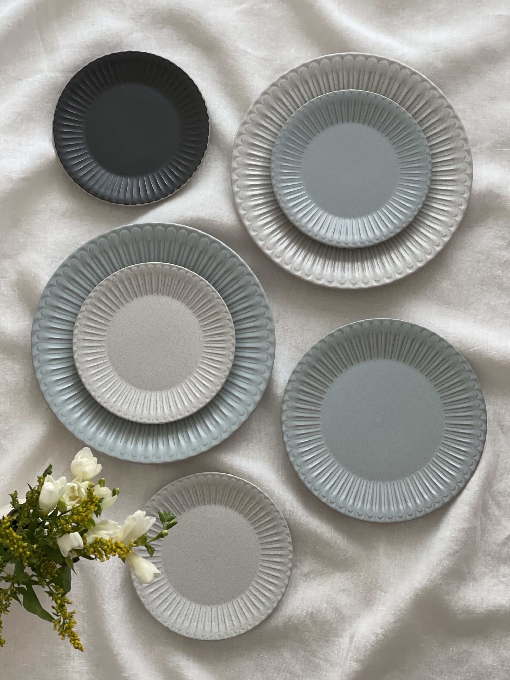 Elegant Storia Plate set with soft lace edges and flecked finish, evoking nostalgia and romance, displayed on a white tablecloth.