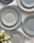 Elegant Storia Plates with lace edges and flecked finish on a table, evoking nostalgia and romance, made of porcelain.