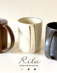 Rila Brown Straight Mug with textured porcelain from Kaneko Kohyo, Japan, shown with two other mugs on a table.