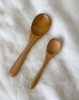 Two natural wooden spoons on a soft white fabric, ideal for soup and children. One spoon is 15.4cm long, made in China.