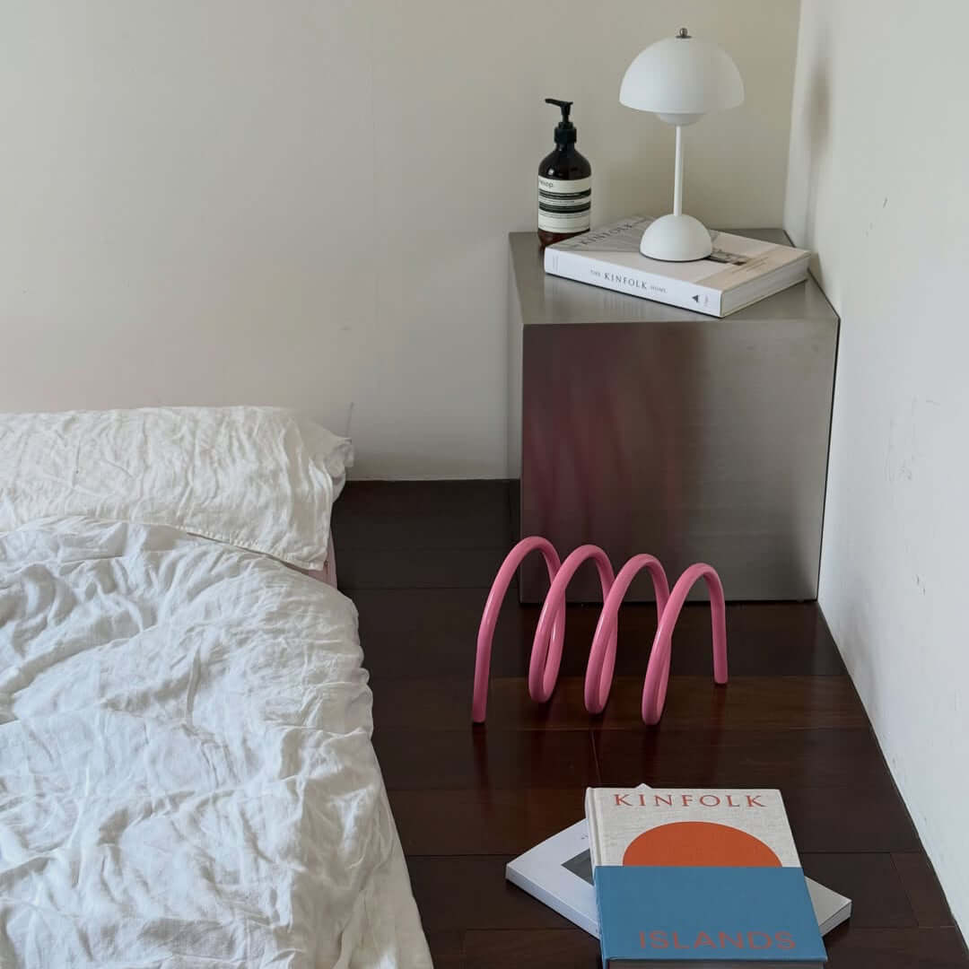 Sculptural spiral book holder on a styled shelf with books and a small clock