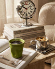Trio Gift Set on a side table: Orbit clock on books, green Crushed mug and Venice cup