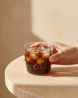 Hand holding the Cherry Glass cup with iced coffee