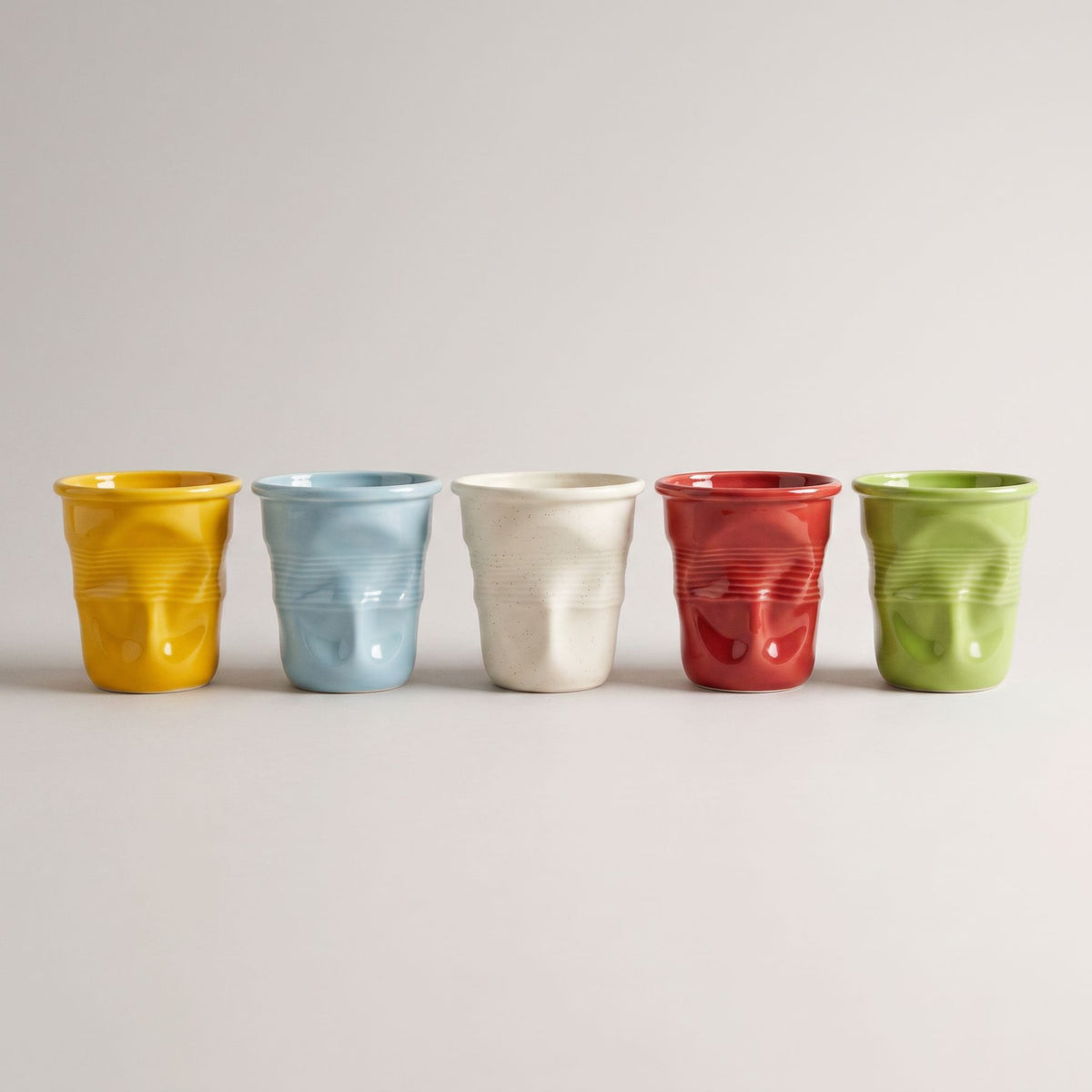 Crushed Ceramic Mugs in yellow, blue, beige, red and green in a row