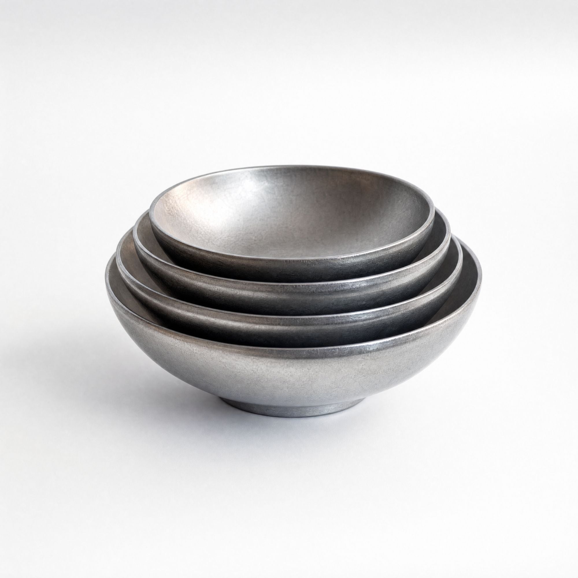 A set of four nested ceramic bowls with a matte, textured gray finish, photographed on a clean white background.
