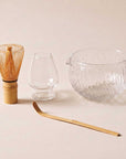 Glass Matcha Ceremony Set laid out: bamboo whisk, glass holder, textured bowl and scoop