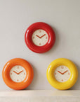 Three Bagel Clocks in red, orange and yellow arranged on a wall