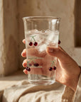 Hand holding the tall Cherry Glass with iced water