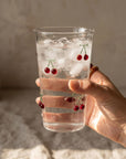 Hand holding the tall Cherry Glass filled with ice and cherries
