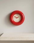 Red Bagel Clock on a wall above a travertine shelf