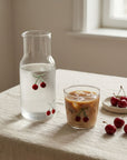 Cherry Glass Pitcher with water beside a Cherry Glass of iced coffee