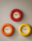 Bagel Clocks in red, orange and yellow on a wall