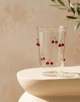 Cherry Glass Pitcher and cup on a white side table with an olive branch
