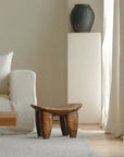 African Senufo wood milk stool with natural textures in a modern living room setting.