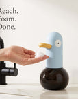 Butter cream duck-shaped automatic foam soap dispenser on a marble bathroom vanity — LoveÉcru" (vary per image: side profile, both colours, foam close-up, refill, in use).