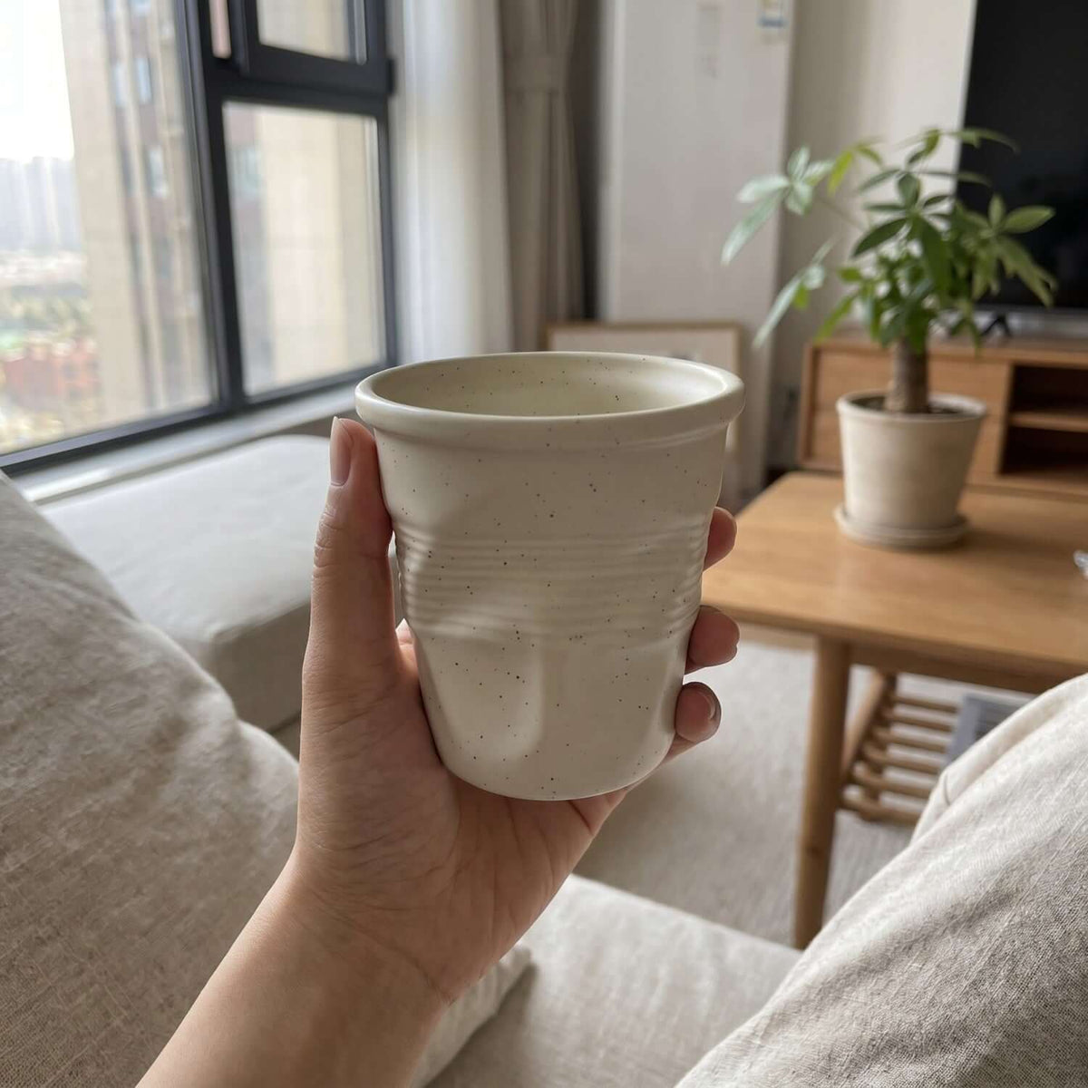 Beige Crushed Ceramic Mug held by a window