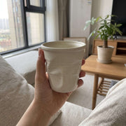 Beige Crushed Ceramic Mug held by a window