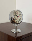 Chrome Orbit Alarm Clock on a dark wooden table