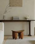 African Senufo wood milk stool in minimalist room setting, highlighting natural textures and retro finish.