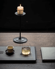 Retro Iron Candlestick with a lit candle on a tray beside a tea cup
