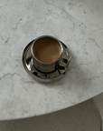 Italian style steel latte coffee cup with saucer on marble table, featuring double-layered design for thermal insulation.