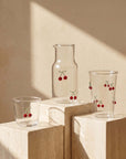 Cherry Glass Pitcher, cup and glass on travertine blocks