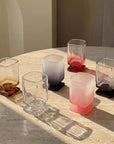Sculpted Pedestal Glasses in clear, brown, black and frosted pink on a stone table