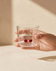 Hand holding the Cherry Glass cup with iced water