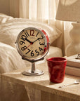Morning Ritual Set with chrome Orbit clock and red Crushed mug on a bedside table