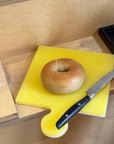 Yellow Lemon Sea Salt Puzzle Pop Chopping Board with a bagel and a knife