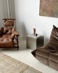 Minimalist Bauhaus Stainless Steel Side Table cube in a living room beside a leather armchair