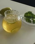 Clair Pitcher with lemon water on a counter with a lemon