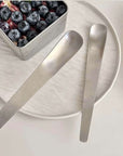 Minimalist Dessert Spoons beside a steel tin of blueberries