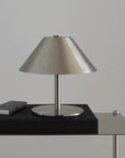 Atelier Halo Lamp, brushed steel conical table lamp on a black side table