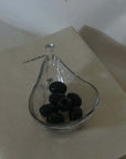 Liora Hand-Blown Glass Scoop Bowl with olives on a white book, angled view