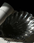 Retro Shell Plate in polished stainless steel beside a book
